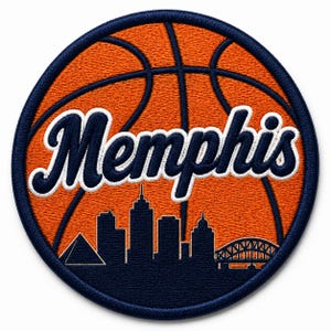 May include: A circular embroidered patch featuring an orange basketball design with dark blue stitching. The word Memphis is written in a white script font across the center, above a dark blue silhouette of the city skyline including a pyramid.