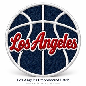 May include: A circular embroidered patch featuring a dark blue basketball design with white stitched lines. The text Los Angeles is embroidered in red with a white outline across the center of the patch, which has a white stitched border.