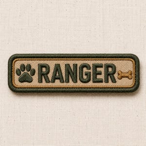 May include: Embroidered patch with a rectangular shape. The patch features the word "RANGER" in dark green block letters, a paw print, and a bone graphic. The patch has a tan background with a dark green border.
