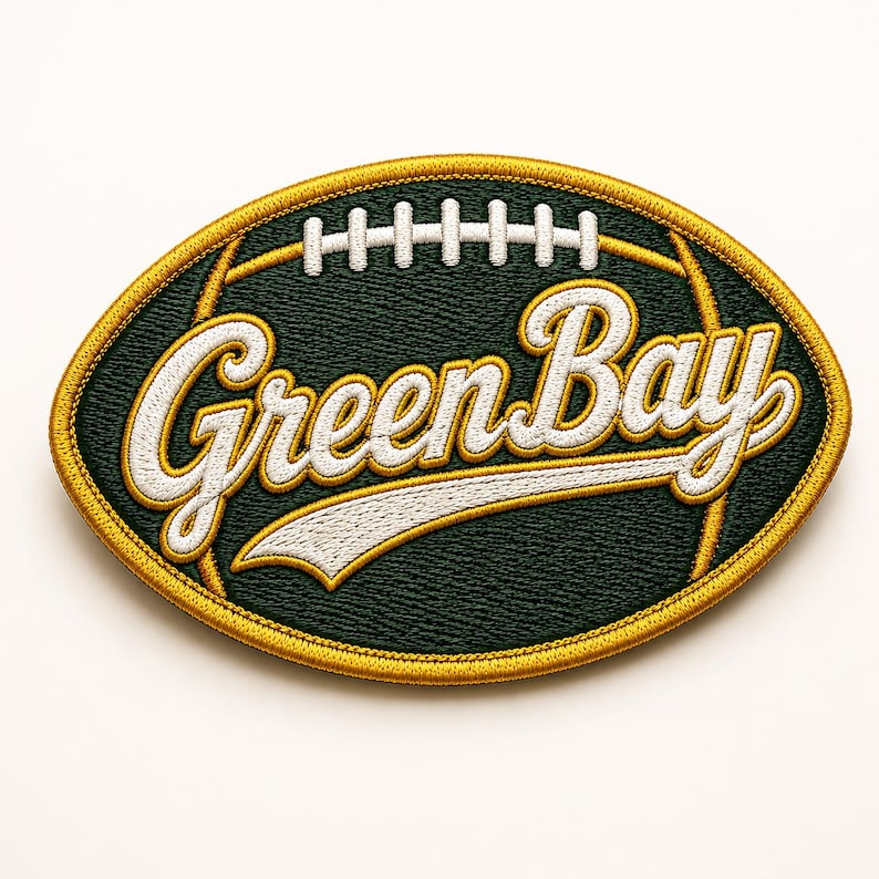 Puede incluir: Parche bordado con forma de bal&oacute;n de f&uacute;tbol americano, con las palabras "Green Bay" en escritura estilizada. El parche tiene un fondo verde oscuro con detalles blancos y dorados, y un borde dorado.