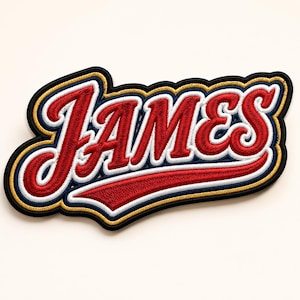 May include: An embroidered patch featuring the name JAMES in a red script font with a white outline, a navy blue border, and a gold accent layer. The lettering is stylized with a long red underline swoosh extending from the final letter S.