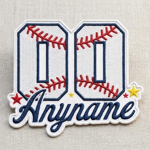 May include: Embroidered baseball patch featuring the number "00" in a white, baseball-stitched design with red stitching. The patch includes the word "Anyname" in a navy blue script font, with red and yellow star accents. The patch is on a beige background.