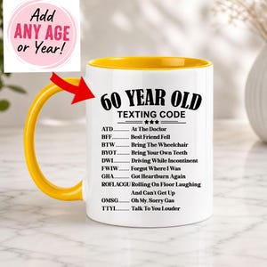 May include: White ceramic mug with a yellow interior and handle. The mug features the text "60 YEAR OLD TEXTING CODE" with a list of acronyms and their meanings. A pink circle with the text "Add ANY AGE or Year!" is in the upper left.
