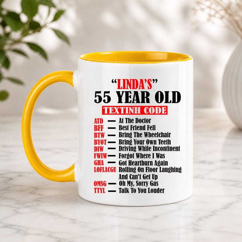 May include: A white ceramic mug with a yellow handle and interior. The mug features the text "LINDA'S 55 YEAR OLD TEXTINH CODE" with a list of humorous acronyms and their meanings, such as "ATD - At The Doctor."