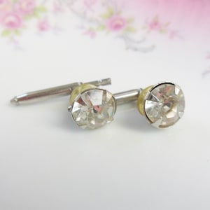 May include: A pair of silver cufflinks with clear rhinestone accents.
