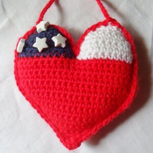 May include: A red, white, and blue crocheted heart with white star embellishments. The heart has a loop for hanging.