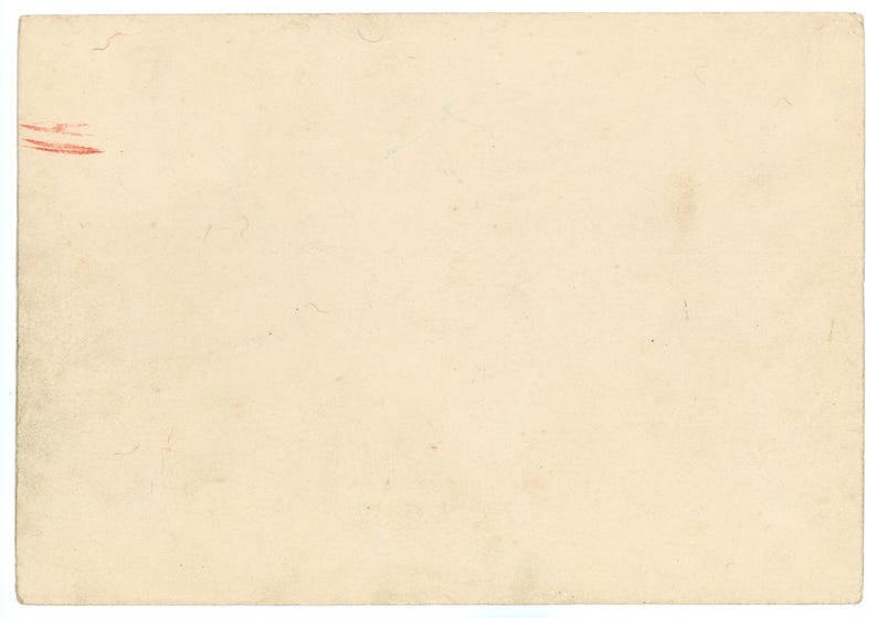 May include: A rectangular piece of aged paper in a light beige tone. The paper has a slightly textured surface with small imperfections and a few faint marks. A small red mark is visible in the upper left corner.