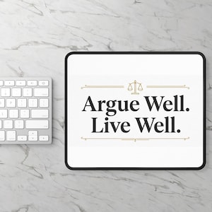 May include: A white rectangular mousepad with the text "Argue Well. Live Well." in black, with a gold scale icon. The mousepad has a black border and sits on a marble surface, next to a white keyboard.
