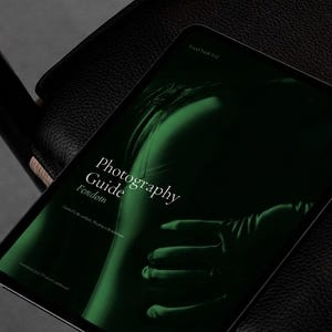 Puede incluir: Una tableta digital que muestra una imagen en tonos verdes con el texto "Photography Guide Feindom". La tableta descansa sobre una superficie de cuero negro, lo que sugiere un tema profesional o artístico. La estética general es moderna y minimalista.