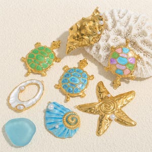 Puede incluir: Una colección de piezas de joyería doradas y coloridas con temática marina. Incluye diseños de tortugas, conchas, estrellas de mar y vidrio marino. La joyería presenta detalles de perlas y colores vibrantes como verde, azul y morado.
