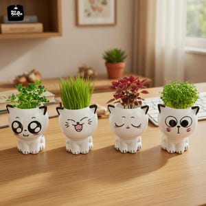 May include: Four white ceramic cat-shaped planters with different facial expressions, each holding a different type of plant. The plants include green grass, red leafy plants, and small green plants. The planters are on a wooden surface.