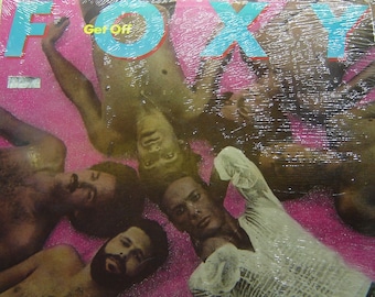 May include: A vinyl record album cover with the title "FOXY" in large blue letters and the words "Get Off" in smaller blue letters. The cover features a group of men lying on a pink background.