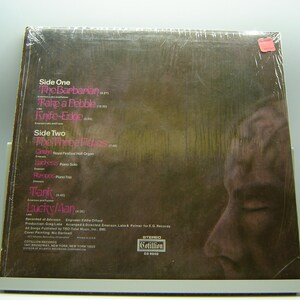 K&ouml;nnte beinhalten: Ein braunes Vinyl-Schallplattencover mit einem Foto eines M&auml;nnergesichts. Das Album tr&auml;gt den Titel "Tank" von "Lucky Man" und enth&auml;lt die Songtitel "The Barbarian", "Take a Pebble", "Knife-Edge", "The Three Fates", "Clytemnestra", "Ladness", "Aroopa", "Tank" und "Lucky/Man".