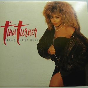 Könnte beinhalten: Ein Vinyl-Plattencover mit Tina Turner in einer schwarzen Lederjacke und einem schwarzen Kleid. Der Albumtitel "Break Every Rule" ist in roten Buchstaben gedruckt.