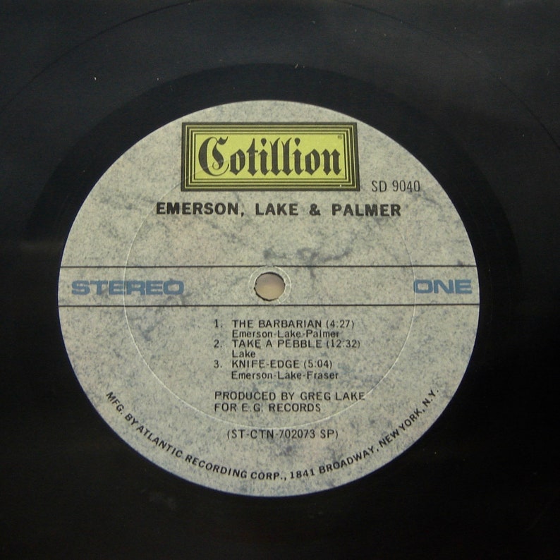K&ouml;nnte beinhalten: Ein wei&szlig;es Vinyl-Schallplattenlabel mit schwarzem Text. Das Label ist f&uuml;r das Album "Emerson, Lake & Palmer" von Cotillion Records. Die Albumnummer ist SD 9040. Die Schallplatte ist Stereo und Seite eins. Die Trackliste enth&auml;lt "The Barbarian", "Take a Pebble" und "Knife-Edge".