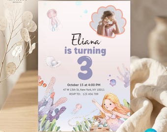 Puede incluir: Una tarjeta de invitación de cumpleaños con temática oceánica, una sirena, medusas, coral y un marco de fotos en forma de concha. El texto dice Eliana is turning 3, October 15 at 4:00 PM, 47 W 13th St, New York, NY 10011, y RSVP TO: 123 456 789.