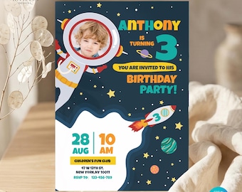 Puede incluir: Una tarjeta de invitación de cumpleaños con temática espacial sobre un fondo azul oscuro con estrellas, planetas y un cohete. Incluye un marco circular para fotos de un niño con traje de astronauta, el texto Anthony is turning 3 y los detalles.