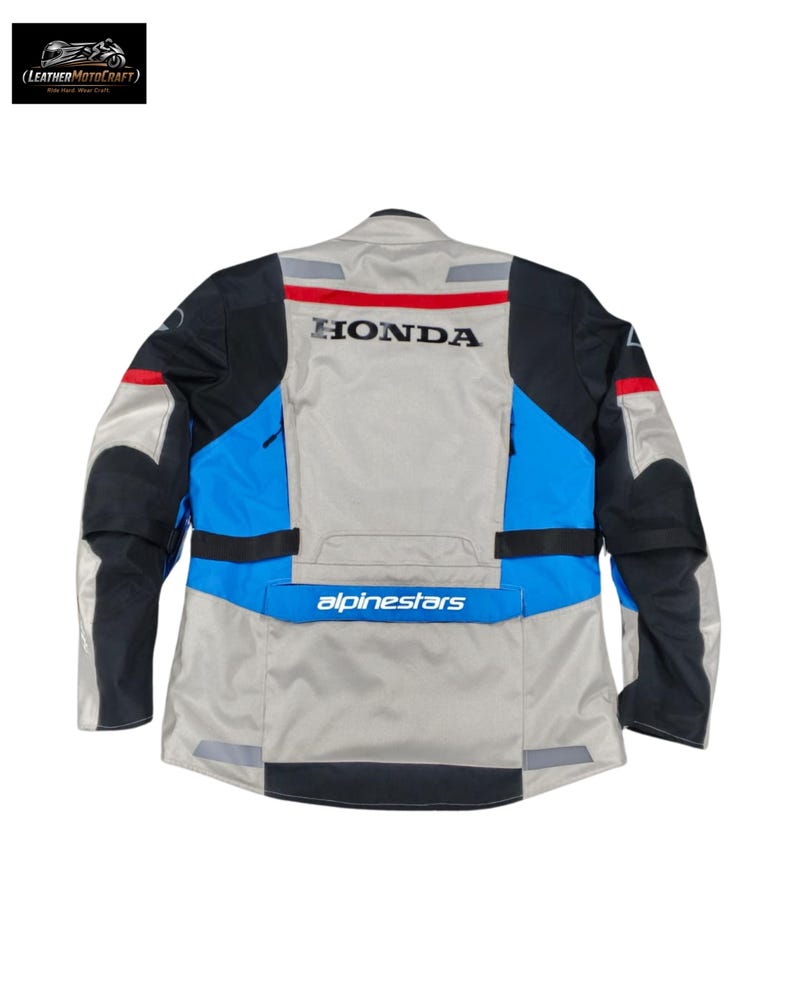 May include: Motorcycle jacket in gray, black, and blue with the "HONDA" logo across the back. The jacket features reflective stripes and the "alpinestars" logo. The jacket is designed for motorcycle riding.