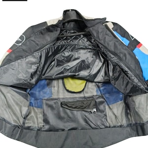 May include: Black, blue, and white motorcycle jacket with a quilted interior. The jacket has a zipper closure, multiple pockets, and a mesh lining. The logo "(LEATHERMOTOCRAFT) Ride Hard, Wear Craft" is visible in the upper left corner.