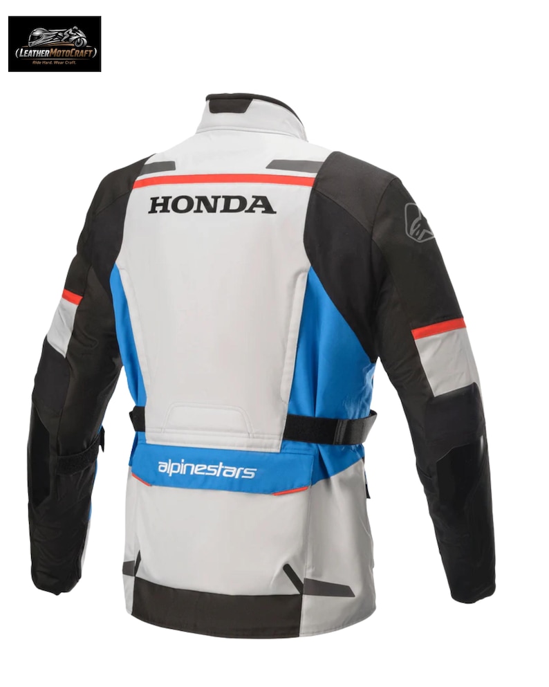 May include: Motorcycle jacket with a white, black, and blue color scheme. The jacket features the "HONDA" logo across the back, with "alpinestars" branding below. The jacket has a high collar and a belt at the waist.