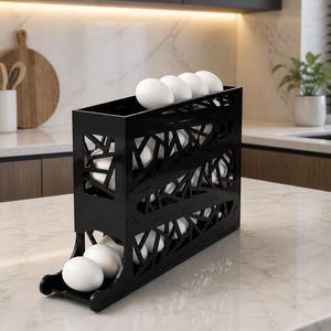 May include: A black, geometric egg holder filled with white eggs. The holder has a modern design with cut-out patterns and is placed on a marble countertop in a kitchen setting. The eggs are visible through the open sides.