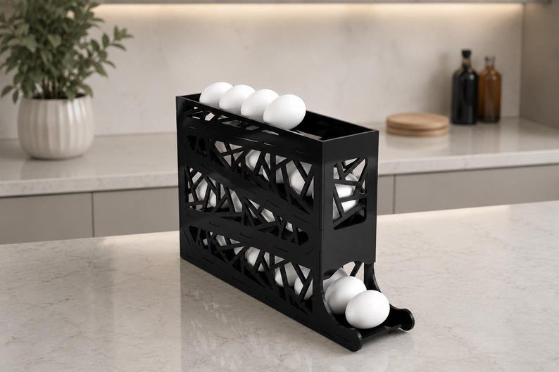 May include: Black egg holder with a geometric design, holding several white eggs. The holder is made of a dark material and has a tiered design for easy access. The kitchen item is on a marble countertop.