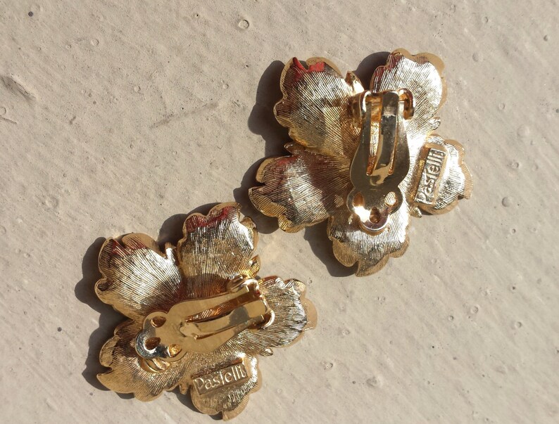 May include: A pair of gold-tone flower-shaped clip-on earrings with the word "Pascielli" engraved on the back.