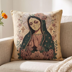 May include: A square throw pillow featuring a woven tapestry design of a figure with closed eyes and hands pressed together in prayer. The figure wears a dark green cloak and is surrounded by pink roses, floral patterns, and two small crosses.