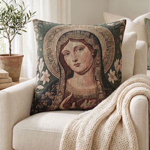 May include: A square throw pillow featuring a woven tapestry design of a woman with a halo, set against a dark green background with floral accents. The image depicts a detailed portrait with intricate textures and a rich, multi-colored palette.