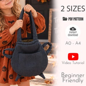 Könnte beinhalten: Eine dunkelgraue Stofftasche in Kesselform mit zwei Griffen und einer Vordertasche. Das Bild enthält den Text: 2 SIZES, PDF PATTERN, instant download, A0 - A4, Video Tutorial und Beginner Friendly. Die Tasche wird von einer Person in einem orangefarbenen Kleid gehalten.