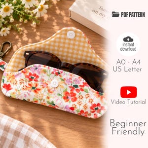 Pode incluir: Um estojo de tecido para óculos com exterior branco com estampa floral vermelha, laranja e rosa e forro interno xadrez vichy amarelo e branco. O estojo inclui um fecho de botão de pressão branco e um clipe de metal. O texto inclui PDF PATTERN, instant download, A0 - A4 US Letter, Video Tutorial e Beginner Friendly.