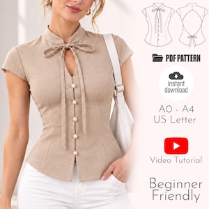 Könnte beinhalten: Eine beige Kurzarmbluse mit Stehkragen, einer Bindeschleife vorne und fünf runden Knöpfen. Das Design enthält ein PDF-Schnittmuster, Sofort-Download, A0, A4, US Letter Formate, ein Video-Tutorial und ist für Anfänger geeignet.