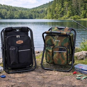 May include: Two portable folding chairs with integrated backpacks, one in solid black and one in a camouflage pattern. The black chair features a brown leather-like patch labeled William, while the camouflage chair displays the name Anthony.