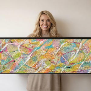 Peut inclure: Une œuvre d'art murale rectangulaire encadrée présentant une peinture expressionniste abstraite à la surface texturée. La composition affiche un mélange vibrant d'éclaboussures et de traînées de peinture jaune, rose, turquoise, bleue et blanche.
