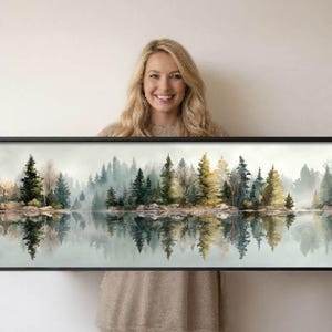 Könnte beinhalten: Ein panoramisches Wandbild in einem schwarzen Rahmen, das einen Wald im Aquarellstil mit immergrünen und laubabwerfenden Bäumen in Grün-, Gold- und Brauntönen zeigt, die sich in einer ruhigen, nebligen Seeoberfläche spiegeln.