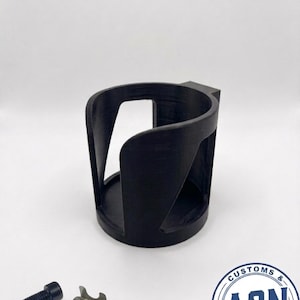 Può includere: Portabicchieri nero stampato in 3D con un design unico, con lati curvi e una base circolare. Include un bullone nero e una clip in metallo argentato. Prodotto da A2N 3D Studio.