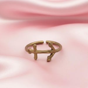 Puede incluir: Anillo ajustable de color dorado con diseño de ancla. El anillo es abierto en la parte superior y tiene un tema náutico. El ancla es un detalle destacado, añadiendo un toque de estilo marítimo a la joya.