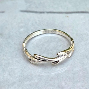 May include: A silver-toned metal ring featuring a textured, organic branch-like design that wraps around the band. The interior of the band is clearly engraved with the text Balajijewellers25 in a small, dark, sans-serif font.