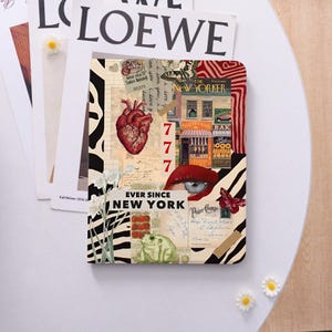 May include: A rectangular notebook featuring a collage design with a red anatomical heart, a green frog, a New Yorker magazine cover, a human eye, butterflies, and the text EVER SINCE NEW YORK. The background includes zebra stripes and vintage paper.