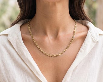 May include: A gold-toned chain necklace featuring a series of interconnected oval links with a central horizontal bar in each link, resting against the collarbone. The necklace has a polished finish and a consistent, repeating link pattern.