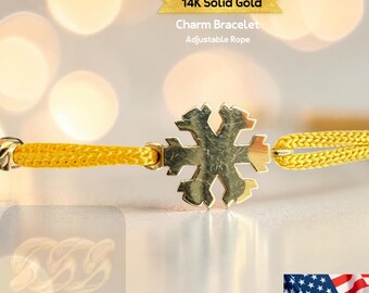 May include: A close-up of a 14K solid gold charm bracelet with an adjustable rope. The bracelet features a gold snowflake charm and a bright yellow rope. The text "14K Solid Gold" and "Charm Bracelet" are visible.