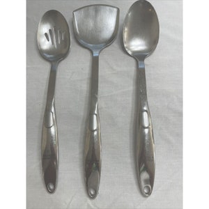 May include: Three stainless steel kitchen utensils: a slotted spoon, a spatula, and a solid spoon.