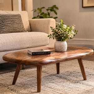 Table basse en bois de teck, plateau arrondi brun chaud et pieds fuselés