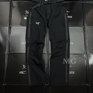 May include: Black outdoor pants with a belt, zippers, and the Arc'teryx logo. The pants have a streamlined design and are made of a durable material. The pants are displayed against a backdrop of black boxes with the Arc'teryx logo.