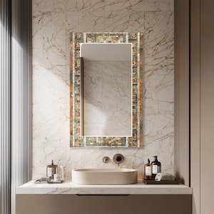 Peut inclure: Un miroir rectangulaire de salle de bain avec un cadre en mosaïque de carreaux dans les tons de marron, vert et beige. Le miroir est monté au-dessus d'un lavabo ovale beige et d'un comptoir en marbre. La salle de bain a un design moderne.