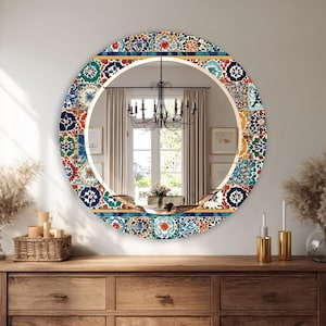 Pode incluir: Um espelho redondo decorativo com um design de mosaico colorido na borda. O mosaico apresenta azulejos azuis, vermelhos, laranja e verdes. O espelho está pendurado em uma parede acima de uma cômoda de madeira.