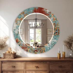 May include: A round decorative mirror with a distressed, patterned border in shades of teal, rust, and gold. The mirror is mounted on a wooden dresser. The mirror's design has a vintage, bohemian aesthetic.