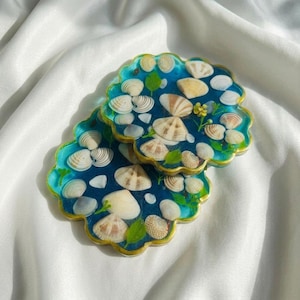 Juego de posavasos de resina con forma de concha marina, con conchas reales y borde dorado, posavasos con diseño costero de olas del océano azul, regalo ideal para la casa de playa.