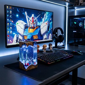 May include: A desktop setup featuring a large monitor displaying a Gundam image, a keyboard, mouse, and headphones. A decorative resin block with a winter scene is in the foreground. The setup is illuminated with blue lighting.