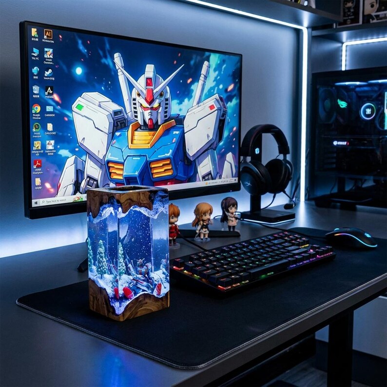 May include: A desktop setup featuring a large monitor displaying a Gundam image, a keyboard, mouse, and headphones. A decorative resin block with a winter scene is in the foreground. The setup is illuminated with blue lighting.